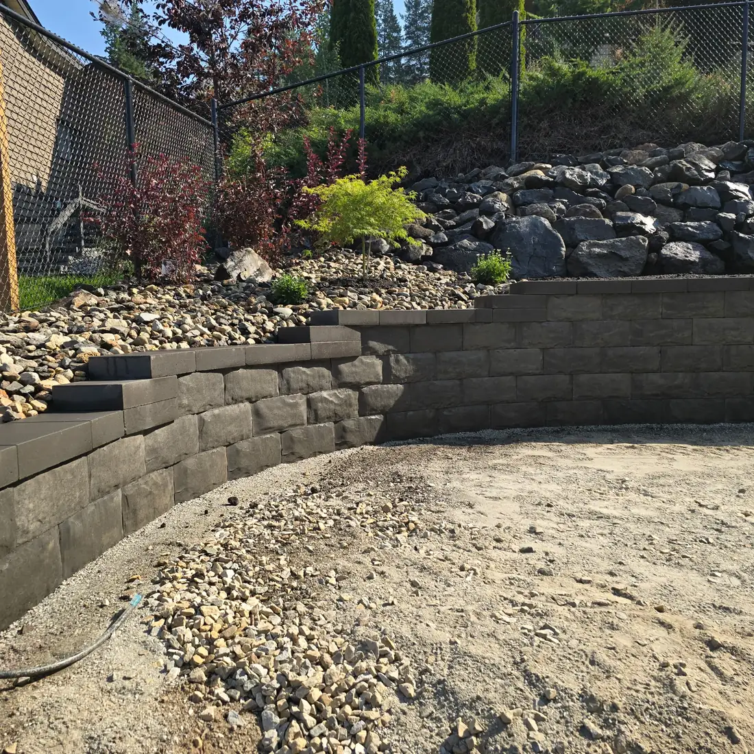 Natural boulder rockwork and rip-rap above a block wall, Eagle Bay BC