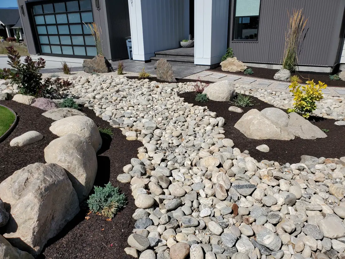Dry riverbed of river rock and set boulders through a front yard, Salmon Arm BC